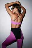 Person wearing a pink sports bra and black leggings with a gray background