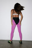Person wearing a black sports bra and pink leggings with a white background