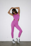 Person wearing a pink jumpsuit with white sneakers on a plain background