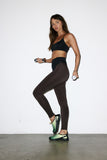 Woman in black athletic wear holding dumbbells against a white background