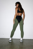 Person wearing a black sports bra and green leggings against a white background