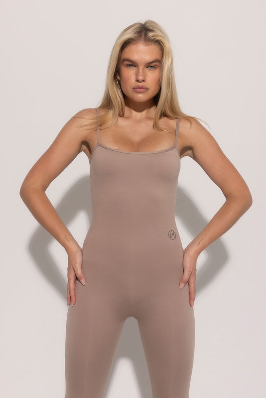 A female model wearing a beige soft sculpt bodysuit with a low scoop back and hidden built-in bra.