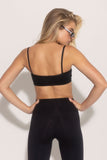 A rear view of a person wearing a black sports bra and matching leggings.