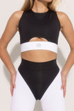 A model wearing a black and white crop top with a front keyhole and cross back design, made from eco tech fabric.