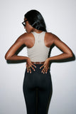 Woman wearing a beige sports bra and black leggings against a white background