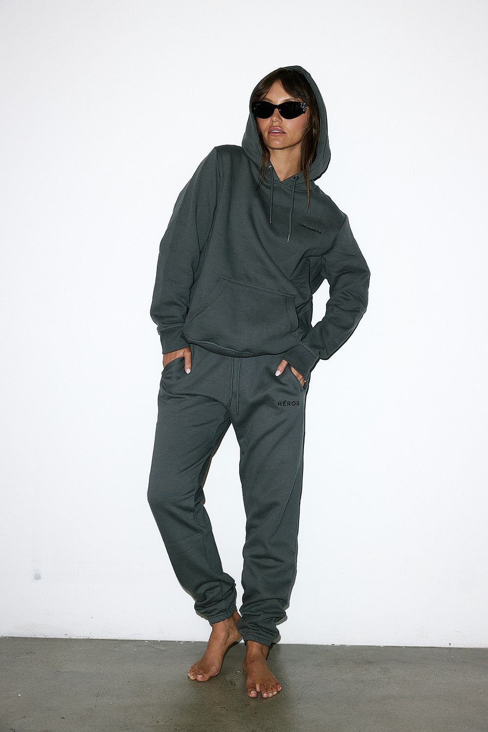 Person wearing a dark green hoodie and pants against a white background