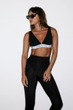 Woman wearing a black sports bra and leggings with 'HEROS' branding on a white background